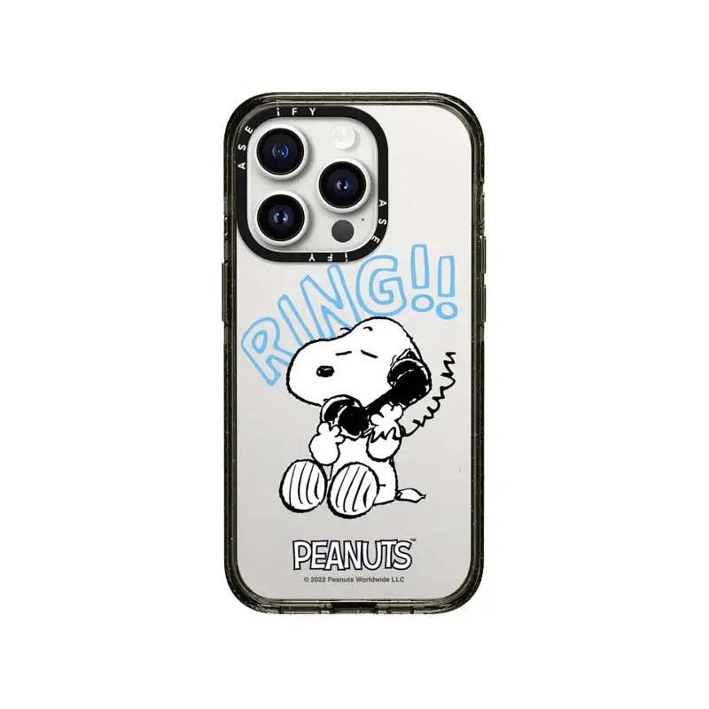 A hand holds a mirror-finish Phone case featuring Snoopy excitedly answering a blue telephone.  The bold blue text "RING!!" appears above him with "PEANUTS" branded below on the reflective surface.