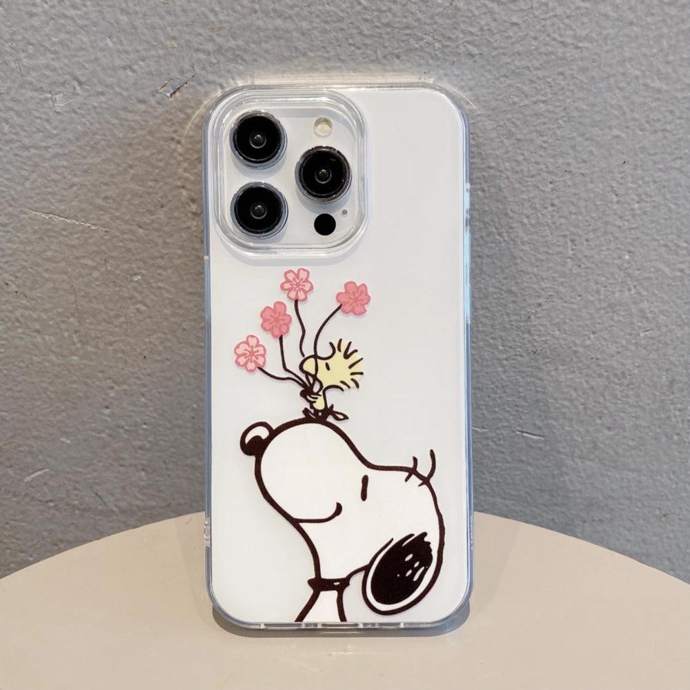 Transparent iPhone case featuring a joyful Snoopy from Peanuts. Woodstock sits on the happy beagle's belly, carefully holding a small bunch of pink flowers in this charming design.